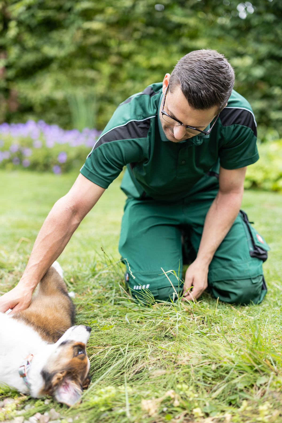 Benjamin Schink bei der Gartenpflege, daneben ein Hund